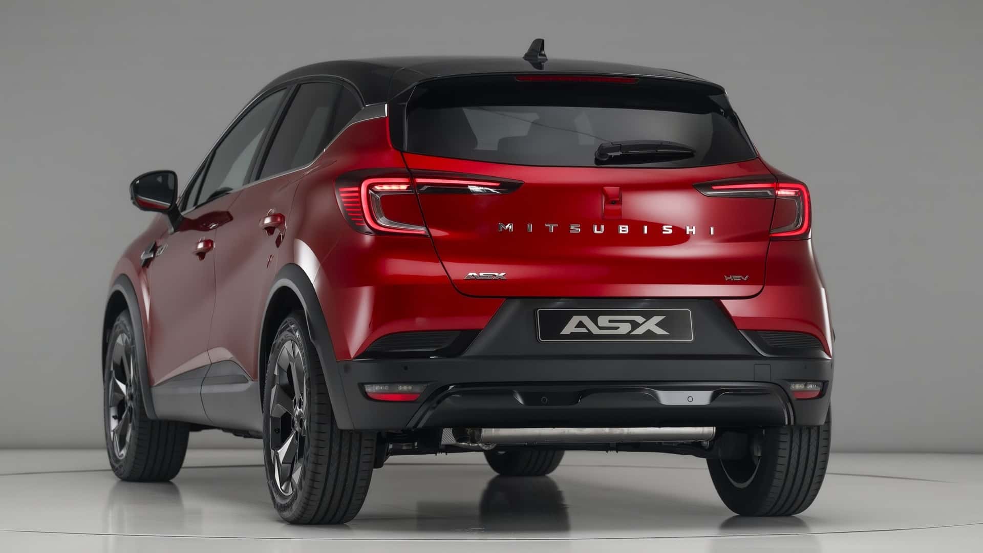 Vista trasera de un SUV Mitsubishi ASX rojo exhibido en un entorno de estudio.