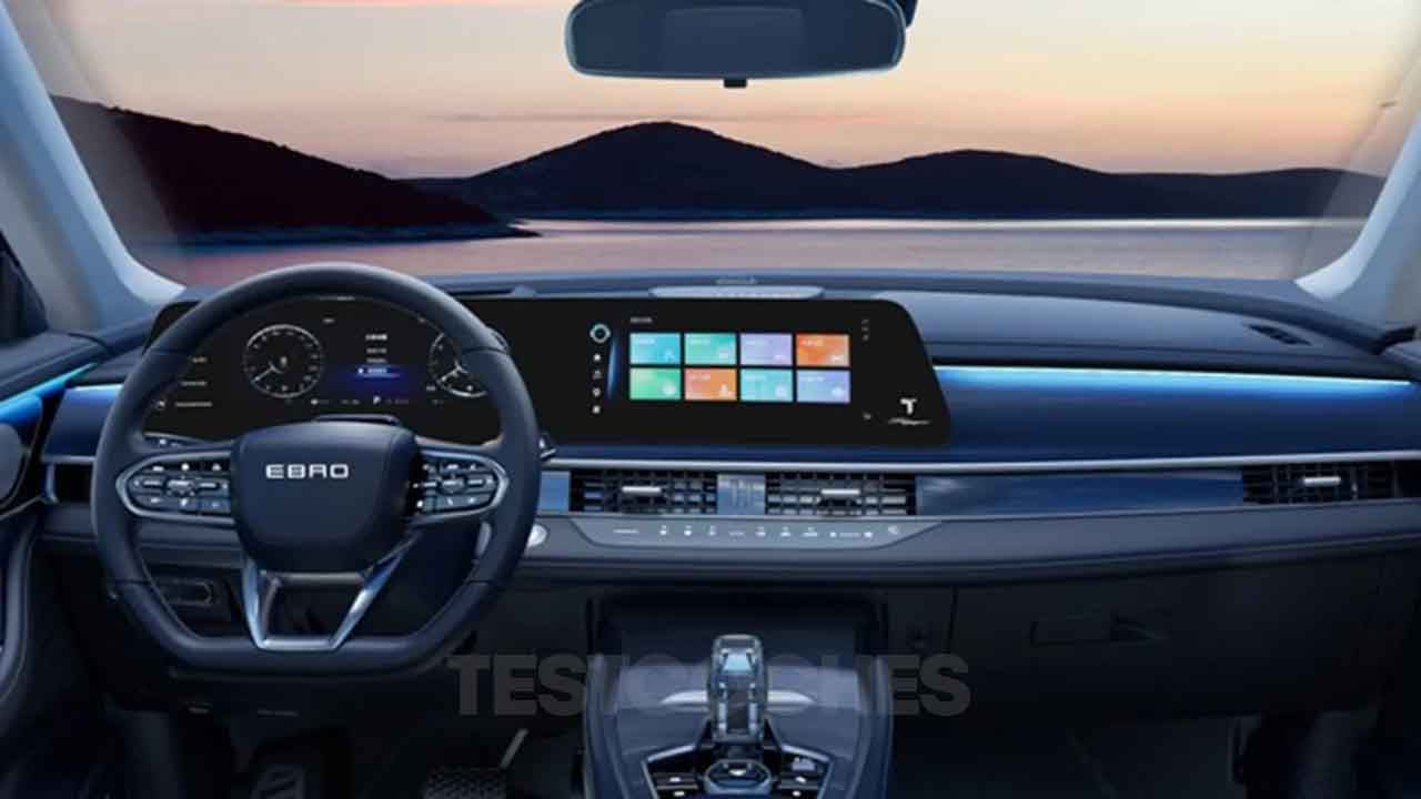 Interior del coche con tablero digital y pantalla táctil, con vista panorámica al lago al atardecer.