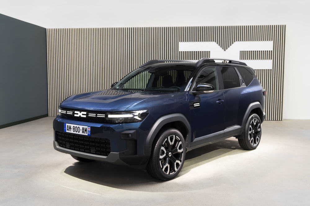SUV azul oscuro estacionado en un lugar cerrado con una pared moderna de rayas verticales al fondo. La matrícula dice "AM 800 AN 6".