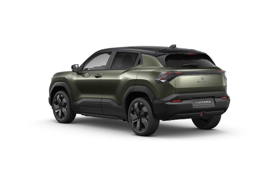 El e Vitara 2025, un SUV verde con un elegante techo negro, capta la atención con su audaz vista trasera y lateral estacionada sobre un fondo blanco prístino.